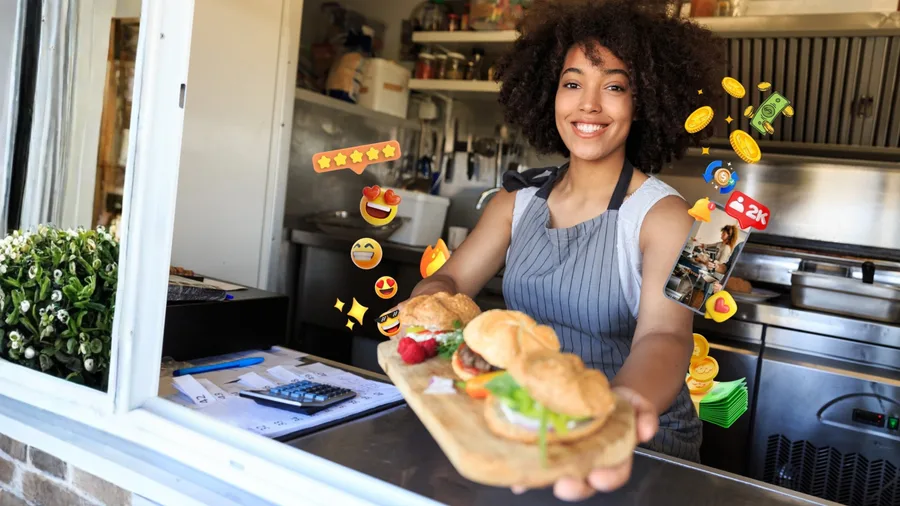 A smiling food entrepreneur offering freshly prepared sandwiches from her kitchen